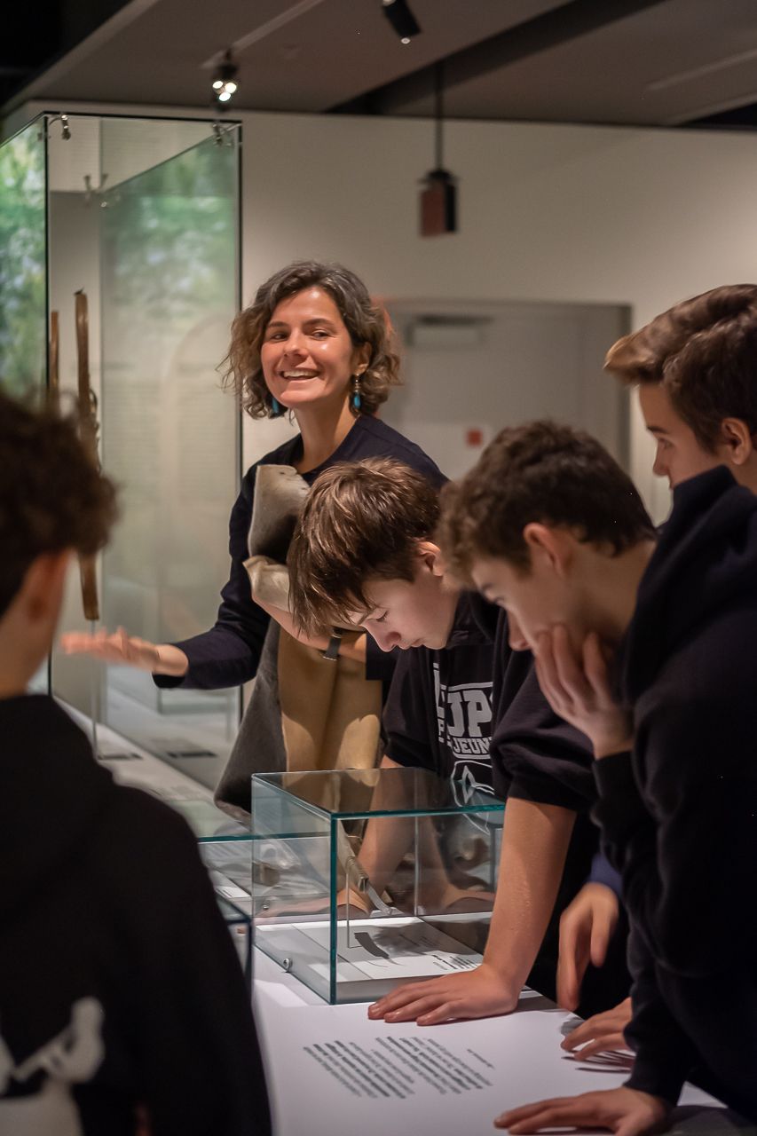  Une femme entourée d'écoliers regarde la caméra en souriant. 